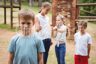 Upset boy with friends gossiping in background