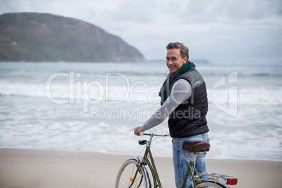 Mature man standing with bicycle on the beach