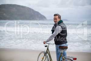 Mature man standing with bicycle on the beach