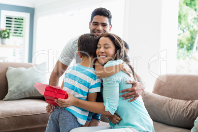 Mother receiving a gift from his kids and husband in living room