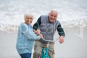 Senior couple standing with bicycles on the beach