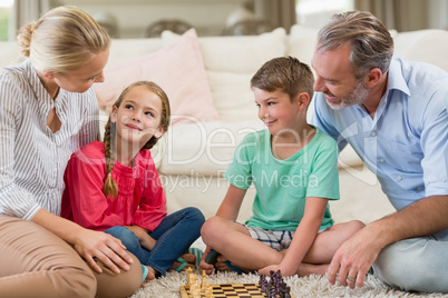 Family playing chess together at home in the living room