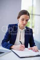 Businesswoman writing on clipboard