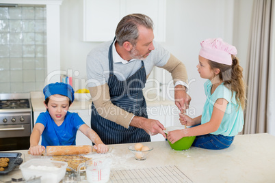 Father and kids preparing food in kitchen