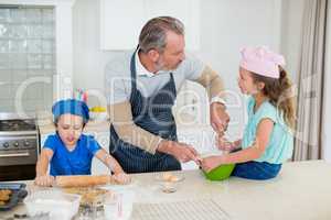 Father and kids preparing food in kitchen