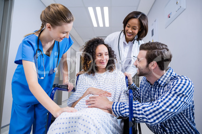 Doctors and man comforting pregnant woman in corridor