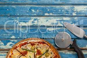 Italian pizza served on pizza tray with cutter and knife on wooden plank