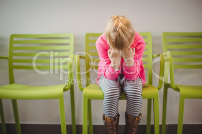 Upset girl sitting on chair in corridor