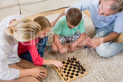 Family playing chess together at home in the living room