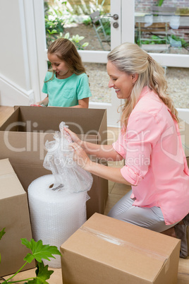 Mother and daughter unpacking carton boxes in living room