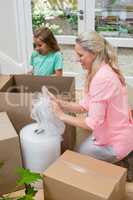Mother and daughter unpacking carton boxes in living room