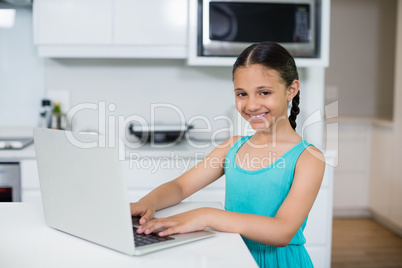 Girl using laptop in kitchen at home