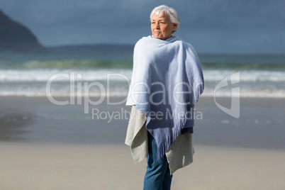 Senior woman wrapped in shawl at beach