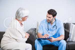 Doctor and senior woman discussing on clipboard