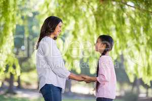 Mother holding hands of her daughter in park
