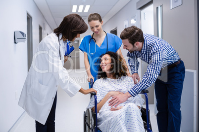 Man and doctors consoling pregnant woman in corridor