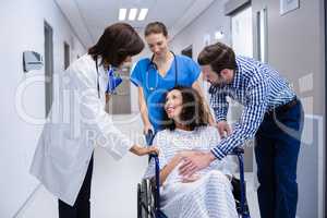 Man and doctors consoling pregnant woman in corridor