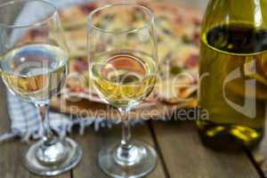 Wine glasses served with pizza in the background