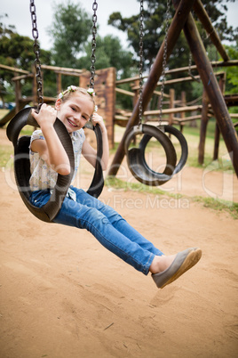 Happy girl sitting on a swing in park