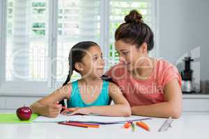 Mother assisting her daughter in doing her homework