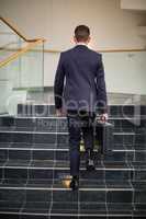 Businessman carrying briefcase climbing up steps