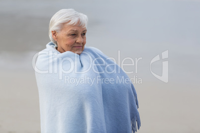 Senior woman wrapped in shawl on the beach