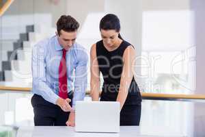 Business executives discussing over laptop