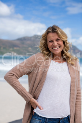 Mature woman with hands behind head standing on the beach