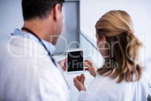 Male and female doctor discussing over digital tablet