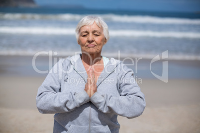 Senior woman praying on the beach