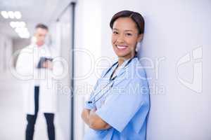 Portrait of female doctor standing with arms crossed in corridor