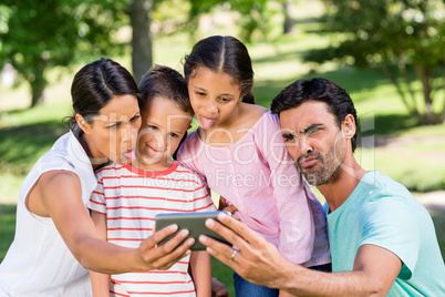 Happy family taking selfie from mobile phone in park