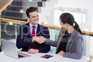 Businessman shaking hands with colleague at desk