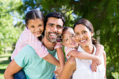 Portrait of parents giving piggy back to their kids in park