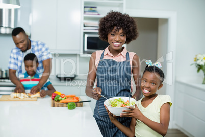 Mother and daughter preparing salad in kitchen at home