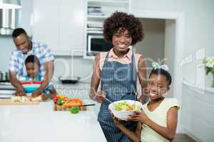 Mother and daughter preparing salad in kitchen at home