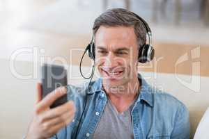 Man listening to music on headphones in living room at home