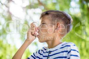 Boy using asthma inhaler in park