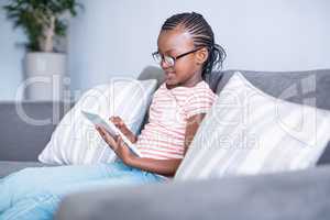 Girl sitting on sofa using digital tablet