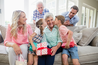 Grandmother receiving a kiss from their grandchildren in living room