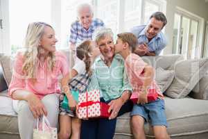 Grandmother receiving a kiss from their grandchildren in living room