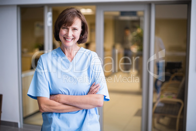 Portrait of smiling nurse standing with arms crossed