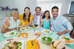 Happy multi generation family having meal on table at home