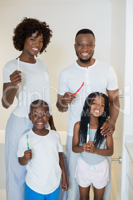 Parents and kids standing with toothbrush in bathroom at home