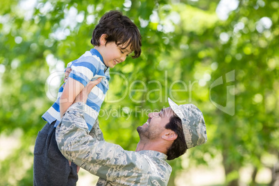 Army soldier lifting boy