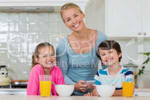 Portrait of mother and kids standing in kitchen