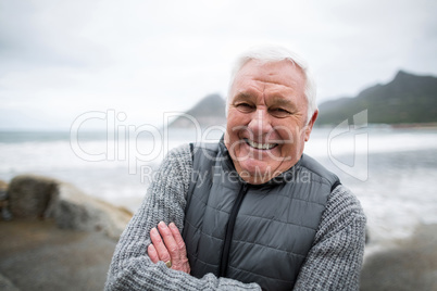 Portrait of senior man standing with arms crossed on the beach