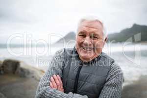 Portrait of senior man standing with arms crossed on the beach