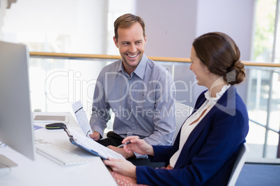 Businesswoman working at desk with colleague