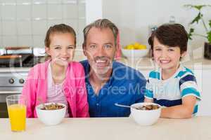 Smiling father and kids having breakfast in kitchen
